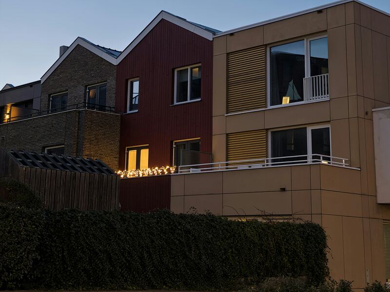Maisons contemporaines en brique et bardage, fenêtres éclairées au crépuscule.