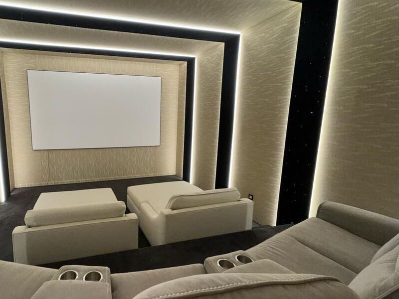 Home cinéma : éclairage d’ambiance, écran et climatisation. Sièges face au grand écran, éclairage LED indirect encadrant les murs.
