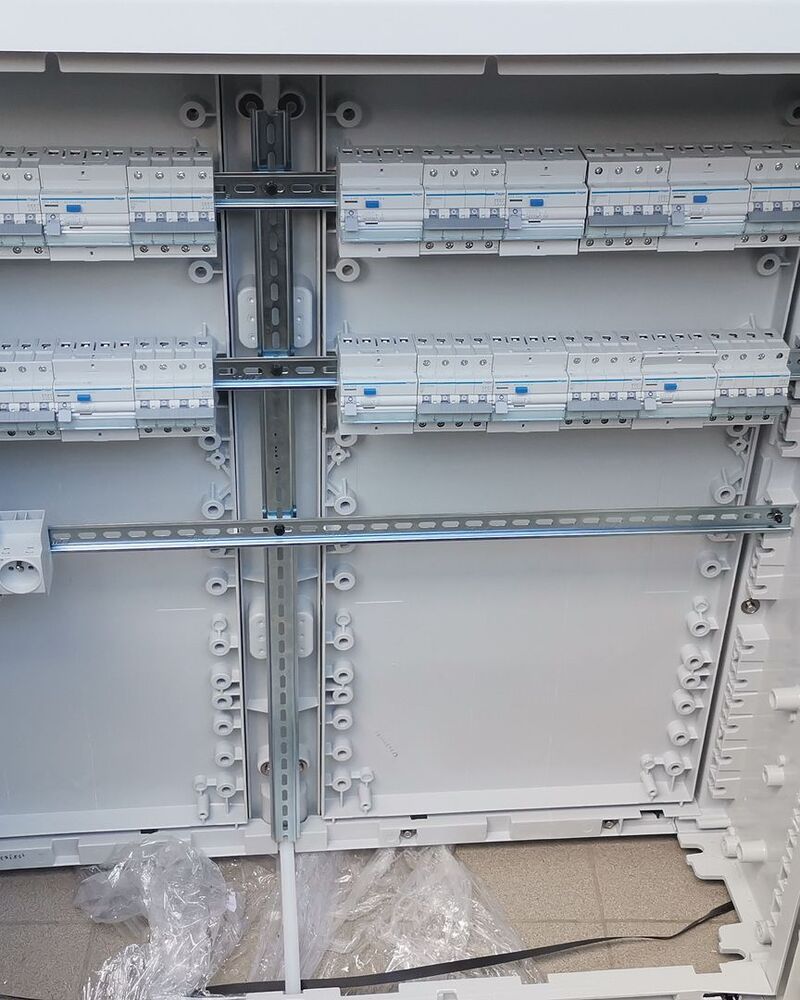 Coffret électrique ouvert, rails DIN et premiers modules en place.