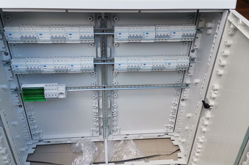 Coffret électrique ouvert, rails DIN et premiers modules en place.